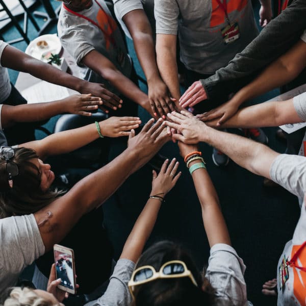 diverse group of people with their arms out and hands together in the middle of the group. Know Your Community